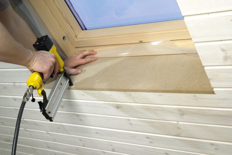 Handyman with a nail gun fixing a window frame.