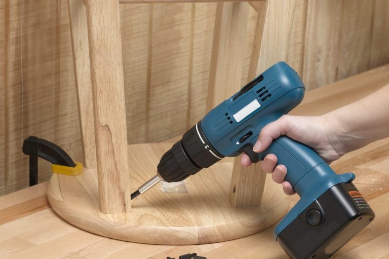 Handyman with a drill assembling a wood chair.