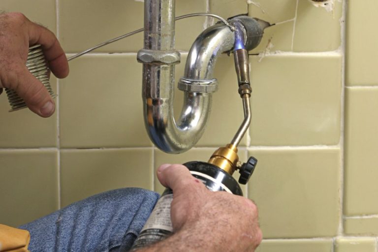 plumber fixing a leak under sink 